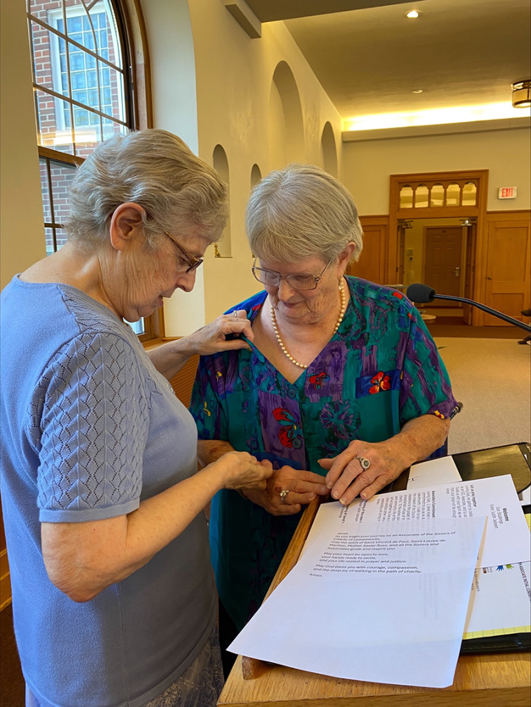 image of a woman placing a pin on the lapel of another woman